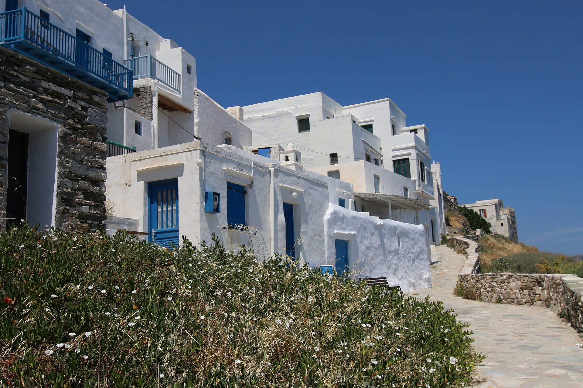 Whitewashed houses with blue balconies along the path on the eastern edge of Kástro, above the sea.