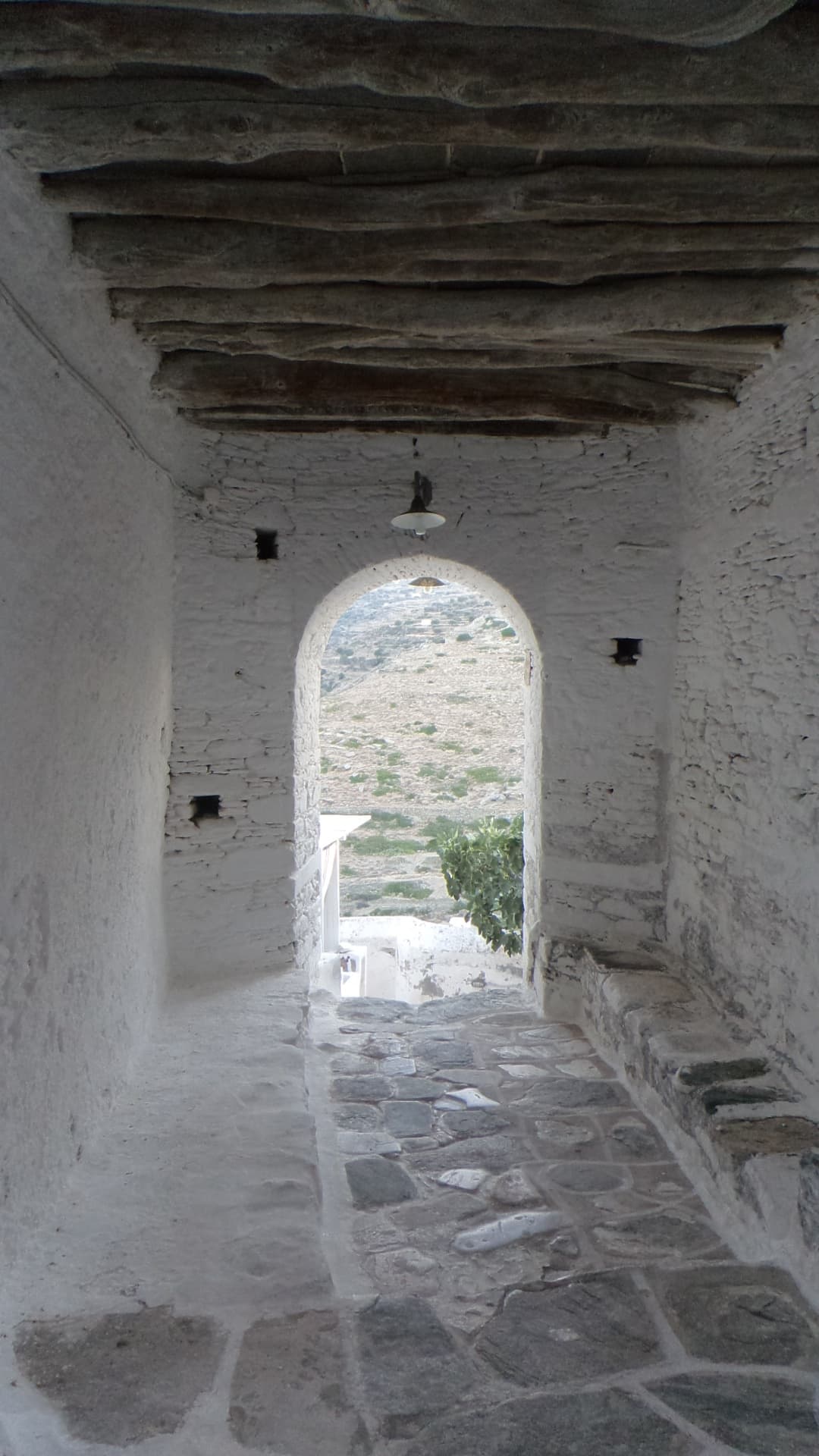A whitewashed vaulted passage in Kástro, Sífnos, with a stone floor.